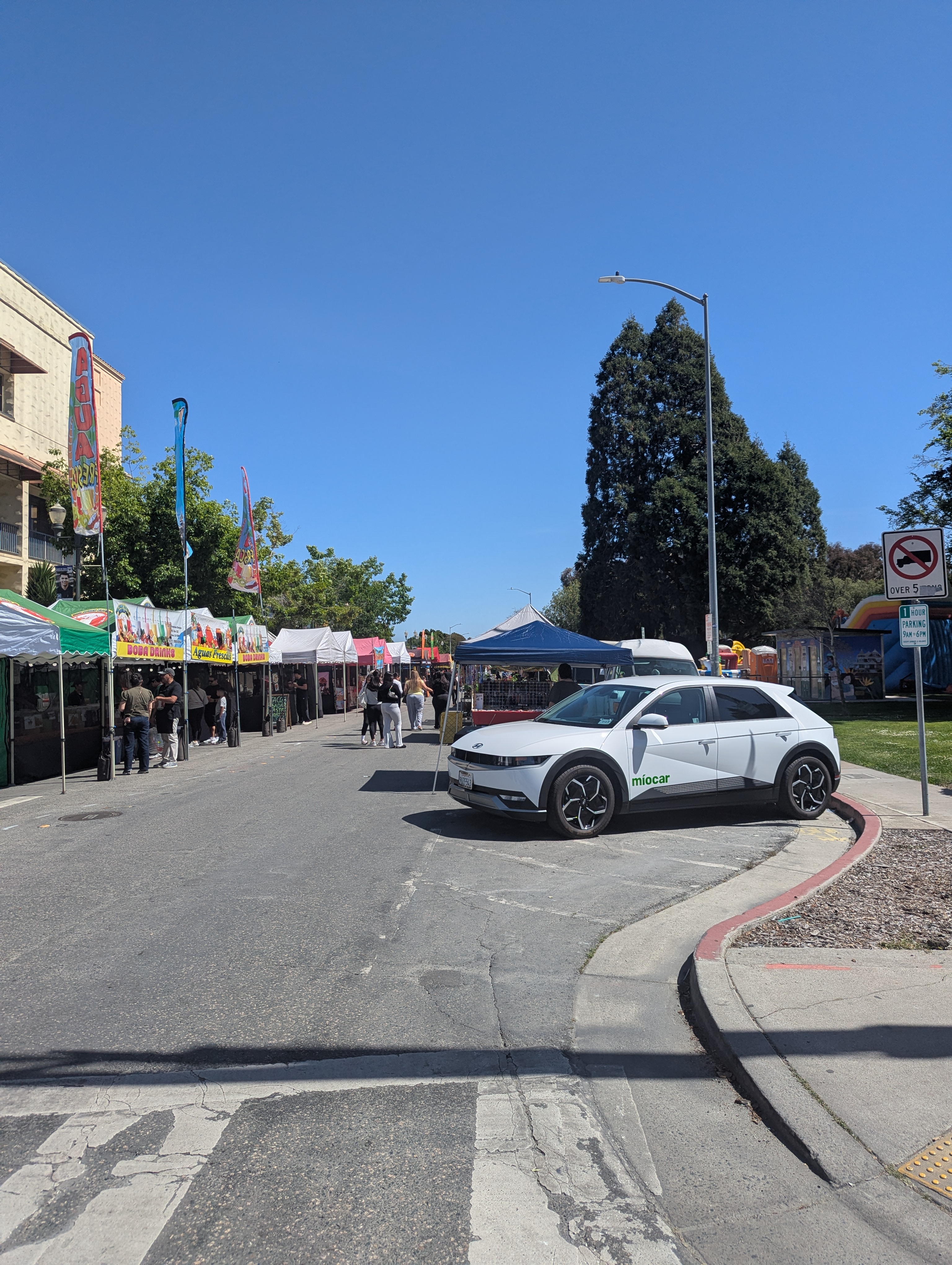 Side view of Miocar EV with booths in the background