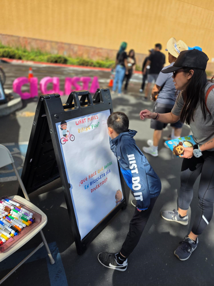 East San Jose Mobility project event with attendees view promotional poster for bikes